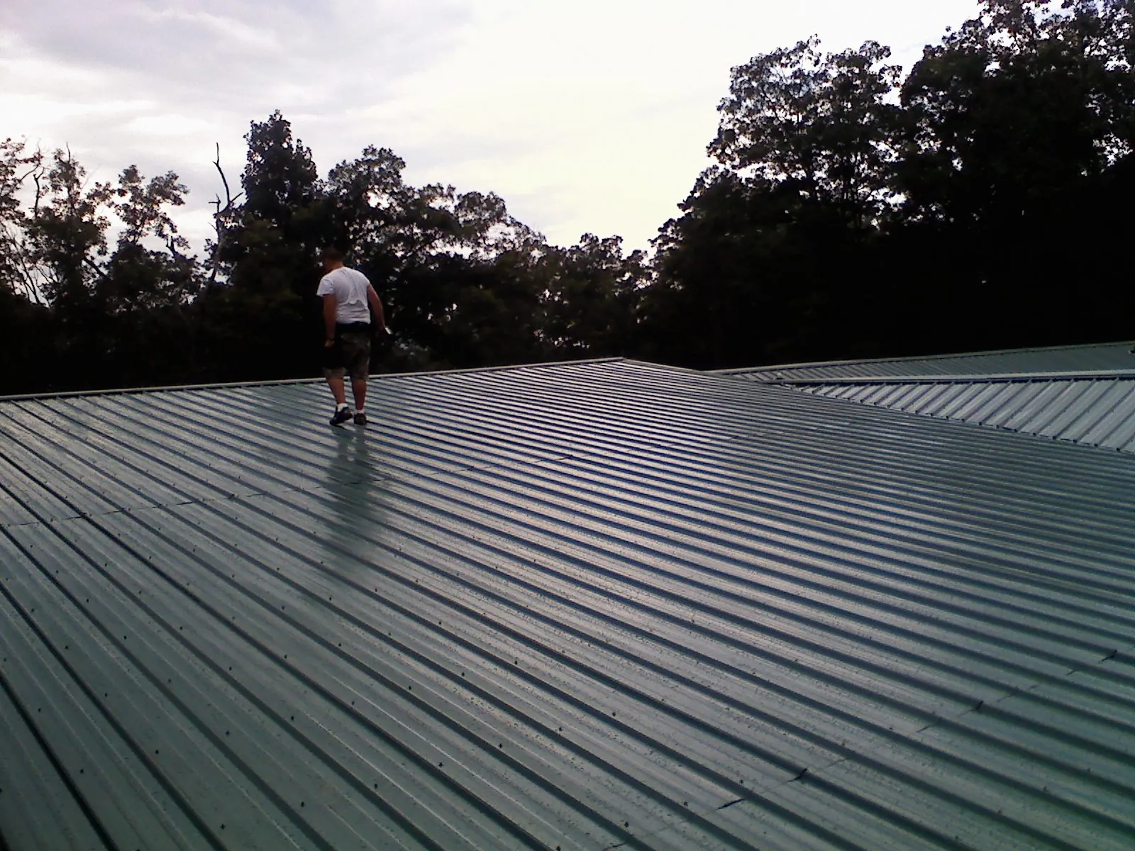 Roofer walking a wide expanse of new green metal roofing in Marysville