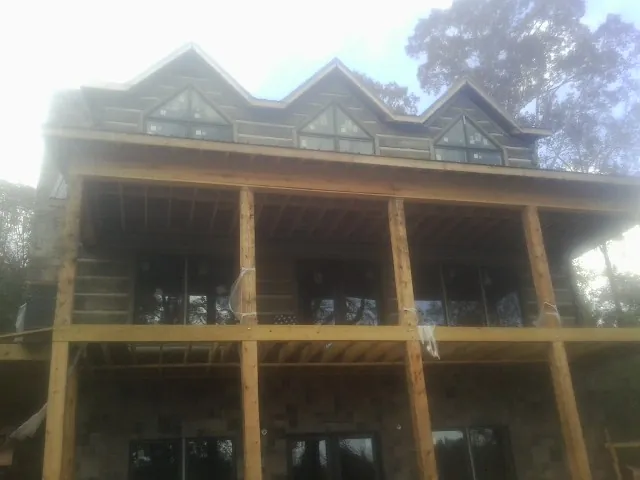 Dormers and porch framing on a large log home under construction — Roof Coating work by our crew in Marysville